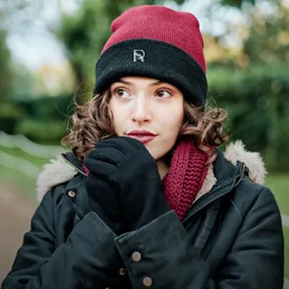 Femme portant un bonnet rouge et un manteau noir avec écharpe en extérieur