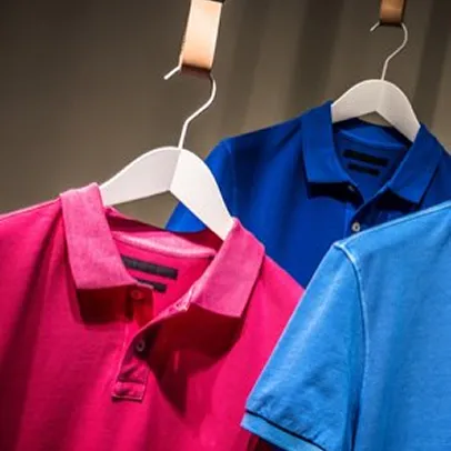 Deux polos personnalisables suspendus sur cintre, bleu et rose vif