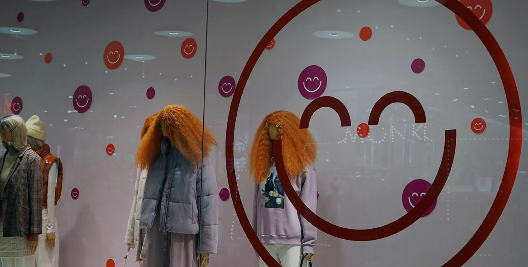 Mannequins stylisés avec vêtements chauds devant vitrine lumineuse à motifs joyeux